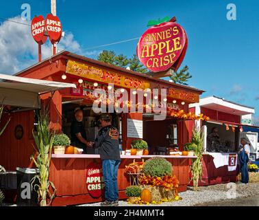 Customer order food at a brightly lit orange food stand selling Apple Crisp at the Deerfield Fair - Deerfield, New Hampshire Stock Photo