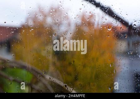 Window with raindrops and blurred background on an autumn rainy day. Weather and season concept. Close up, selective focus Stock Photo