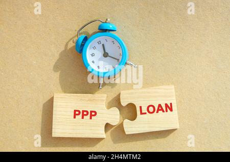 Puzzles with words PPP loan and alarm clock. Paycheck Protection Program. Loan designed to provide a direct incentive for small businesses to keep the Stock Photo