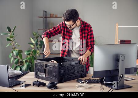 Portrait of attractive focused skilled trendy guy fixing improving motherboard processor at studio office workplace workstation indoor Stock Photo