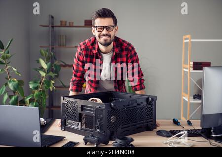 Portrait of attractive smart bearded cheerful trendy guy upgrading processor data tech issue at office workplace workstation indoor Stock Photo