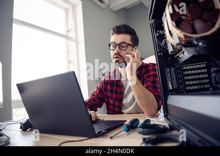 Portrait of attractive smart skilled trendy guy contacting client debugging data code at office workplace workstation indoor Stock Photo