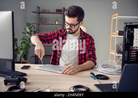 Portrait of attractive skilled experienced serious focused guy repairing fixing broken laptop at office work place station indoor Stock Photo