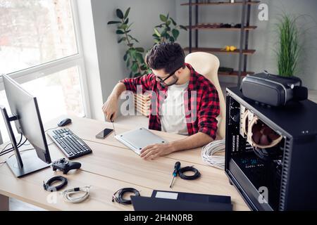 Above high angle view portrait of nice experienced focused guy repairing fixing broken laptop device at office work place station indoor Stock Photo