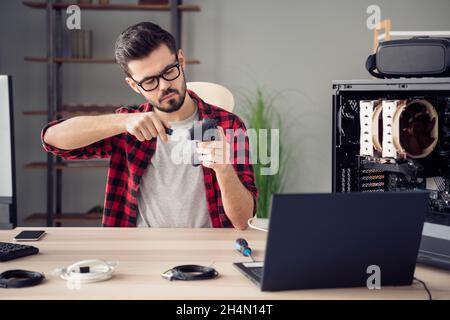 Portrait of attractive focused hardworking skilled trendy guy repairing device gamepad at office workplace workstation indoor Stock Photo