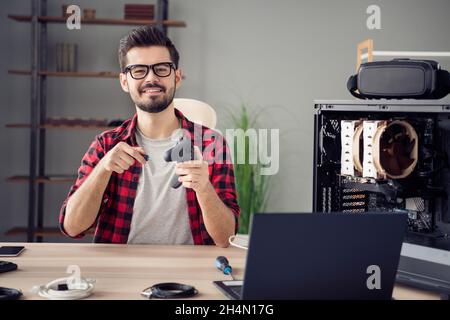 Portrait of attractive cheerful skilled trendy guy repairing device gamepad videogame service at office workplace workstation indoor Stock Photo