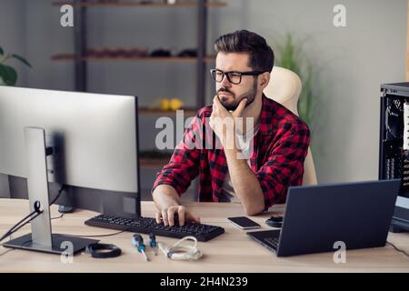 Portrait of attractive qualified minded guy senior web dev programming brainstorming at office work place station indoor Stock Photo