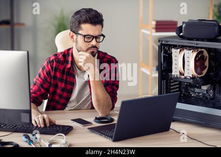 Portrait of attractive skilled qualified serious guy senior dev ops manager programming debugging at office work place station indoor Stock Photo