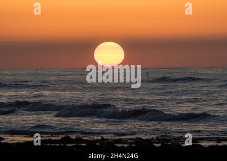 Sun setting over sea at West Runton Beach, Sheringham, North Norfolk Coast Stock Photo