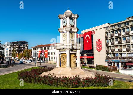 Bursa, Turkey – November 10, 2020. Clock tower in Ataturk caddesi avenue in Bursa, Turkey. View with surrounding buildings on a sunny day. Stock Photo