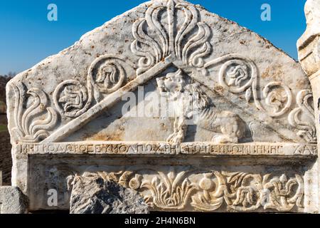 Cavdarhisar, Kutahya, Turkey – November 17, 2020. Triangular fragment of a marble grave stele depicting a lion figure, palmette motifs and a Greek ins Stock Photo