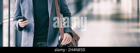 Business man texting using phone walking on travel commute in airport or train station banner panorama. Businessman hand holding cellphone device Stock Photo