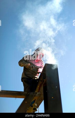 Welder arc-welding a structural steel frame on a construction site Stock Photo
