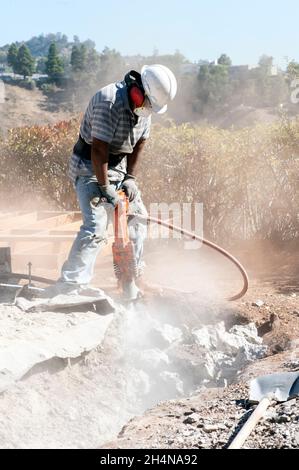 Construction worker using a jackhammer to remove a concrete slab Stock Photo