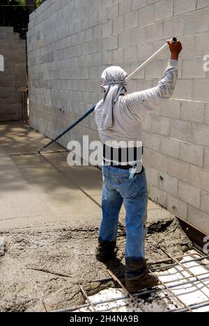 Mason using a bull float to level and smooth a new slab on grade Stock Photo