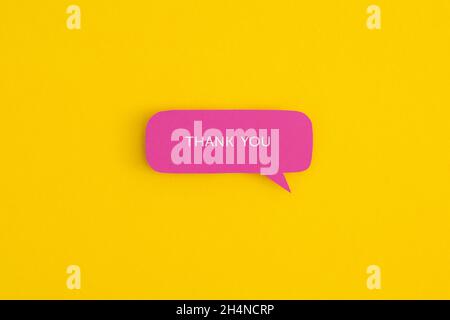 Paper speech bubbles with the word "Thank you" on a yellow background. Top view with copy space. Flat lay. Stock Photo