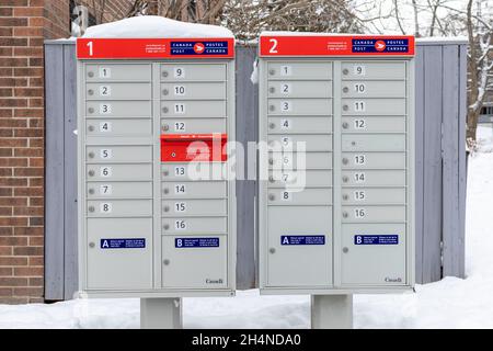 Canada Post mailboxes with red sign in English and French near house in winter Stock Photo