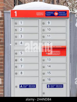 Canada Post mailboxes with red sign in English and French near house in winter Stock Photo