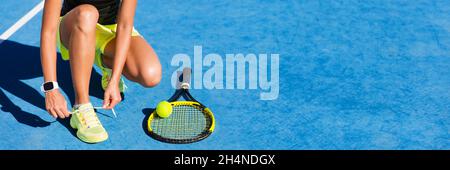 Tennis athlete player on getting ready tying running shoe laces during game on outdoor blue hard court. Banner panorama. Stock Photo