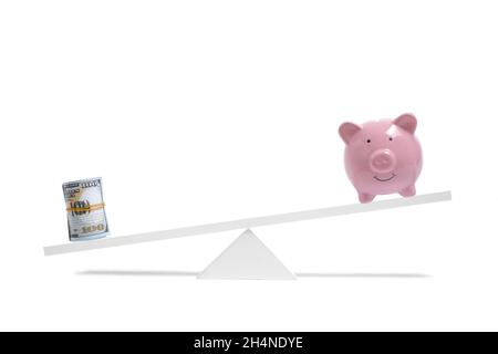 Roll dollar bills on scales outweighs piggy bank, concept saving and spending money Stock Photo