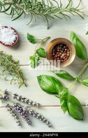 Aromatic herbs with salt and pepper, top shot on a rustic wooden background. Rosemary, lemon balm, basil, thyme, and lavender Stock Photo