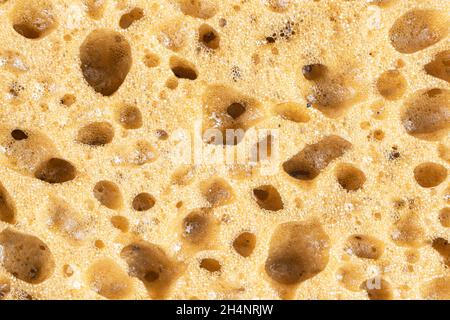 Macro shot of a surface of plastic yellow sponge background. Close-up texture. Yellow scrub sponge pattern. Sponge texture background. Yellow sponge f Stock Photo