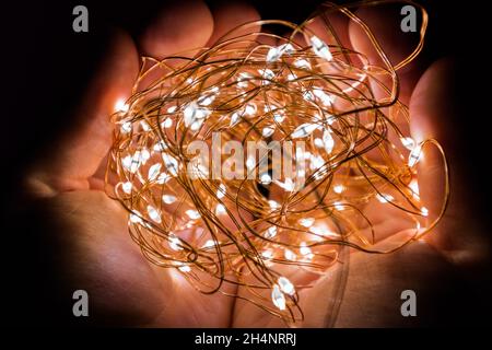Christmas LED garland in hands. Creation of coziness at home for the New Year. Stock Photo
