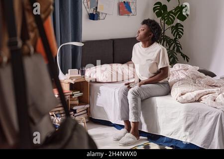 African young woman sitting on the bed in the morning and looking at window Stock Photo