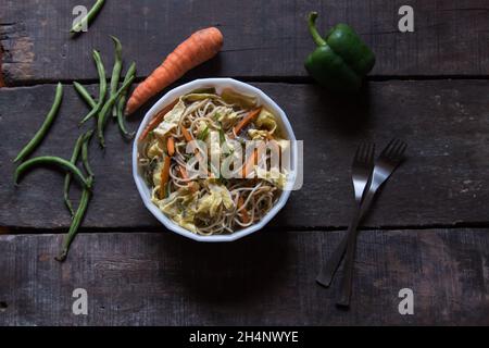 Chinese delicacy schezwan noodles or hakka noodles in a bowl on a background. Top view. Stock Photo