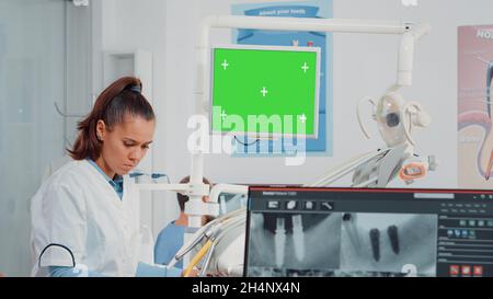 Woman working as dentist with green screen and x ray scan for teethcare in dental cabinet. Oral care specialist analyzing chroma key with isolated mockup template and teeth radiography Stock Photo