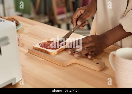Close-up of African woman making toast with jam at the table for breakfast in the morning Stock Photo
