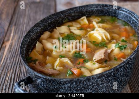 Pot with chicken noodle soup isolated on wooden table Stock Photo