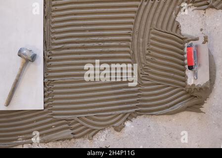 Ceramic large tiles and tools for tiler on the floor unfinished laying floor tiles Floor tiles installation Stock Photo