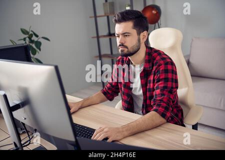 Photo of focused serious young man sit table work office business look screen computer inside indoors Stock Photo