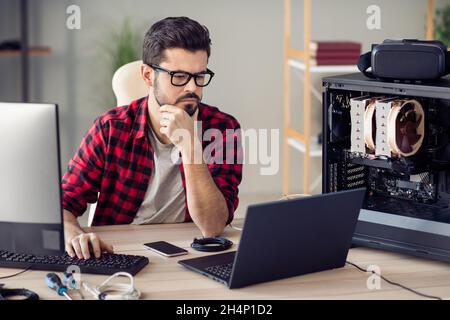 Portrait of attractive skilled qualified serious guy senior dev ops manager programming debugging at office work place station indoor Stock Photo