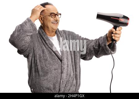 Smiling mature man wearing a bathrobe and using a hair dryer isolated on white background Stock Photo