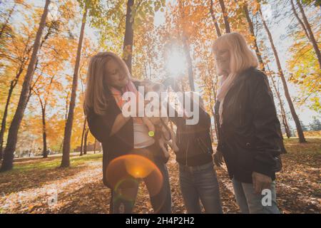 Mother and grandmother and daughter holds jack russell terrier and plays with it in autumn outside. Pet and family concept Stock Photo