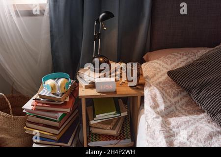Image of bed table with modern alarm clock and books under the table near the bed in the bedroom Stock Photo