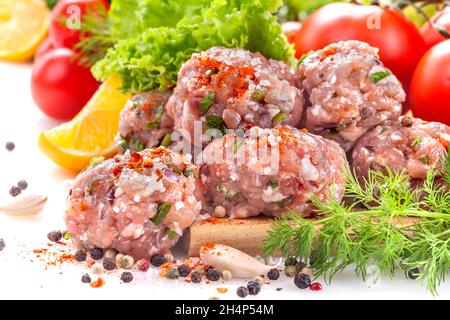 Fresh meatballs with various vegetables on a white background, garnished with spices Stock Photo
