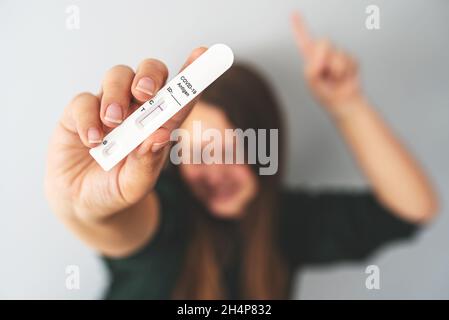 Negative rapid antigen COVID-19 test in hand of unrecognizable blurred person. Happy woman shows her test result. Travel during the coronavirus pandemic, avoid quarantine, new normal concept. Stock Photo