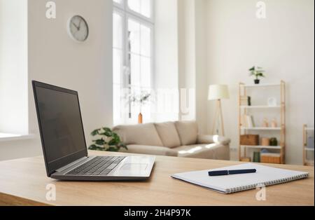 Laptop computer and notebook with pen placed on working desk in empty room at home Stock Photo