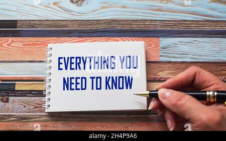Everything you need to know. Motivational quote is written by a stiff hand on a notebook. Striped background. Stock Photo