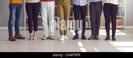 Banner with team of people standing in row in company office, cropped shot of human legs Stock Photo