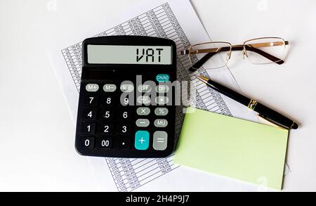 Tax VAT season financing concept written on the display of a calculator that lies on a financial document with glasses and a pen Stock Photo