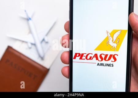 Pegasus airlines logo on the screen of smartphone on the background of passport, ticket and plane, September 2021, San Francisco, USA Stock Photo