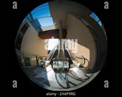 Characteristically exaggerated and distorted circular fisheye view of escalators leading to rooftop gardens and restaurants in the new Westgate Shoppi Stock Photo