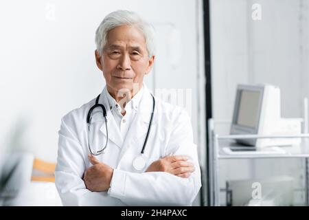 Senior asian doctor standing with crossed arms in hospital Stock Photo