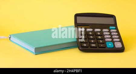 Bookkeeping, financial concept. On a yellow background is a notebook and calculator. Stock Photo