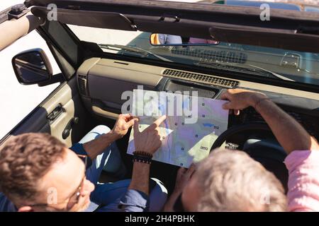 Caucasian gay male couple reading map sitting in car at seaside Stock Photo