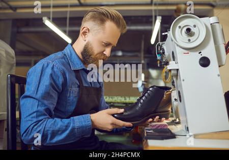 Male shoemaker sewing and checking boot on defect at footwear factory workshop Stock Photo